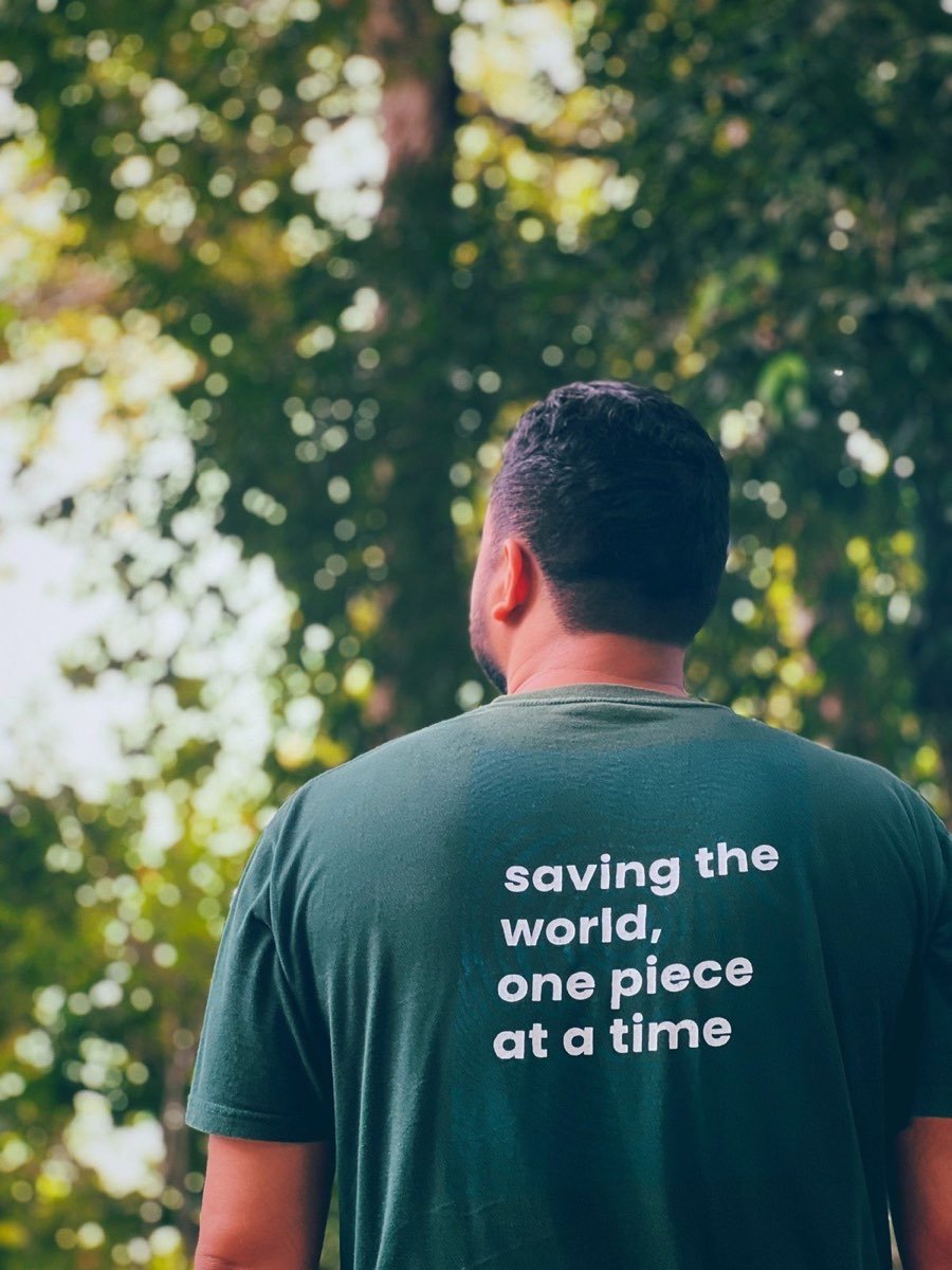 Harith membelakangi kamera dengan baju bertulis saving the world one piece at a time.