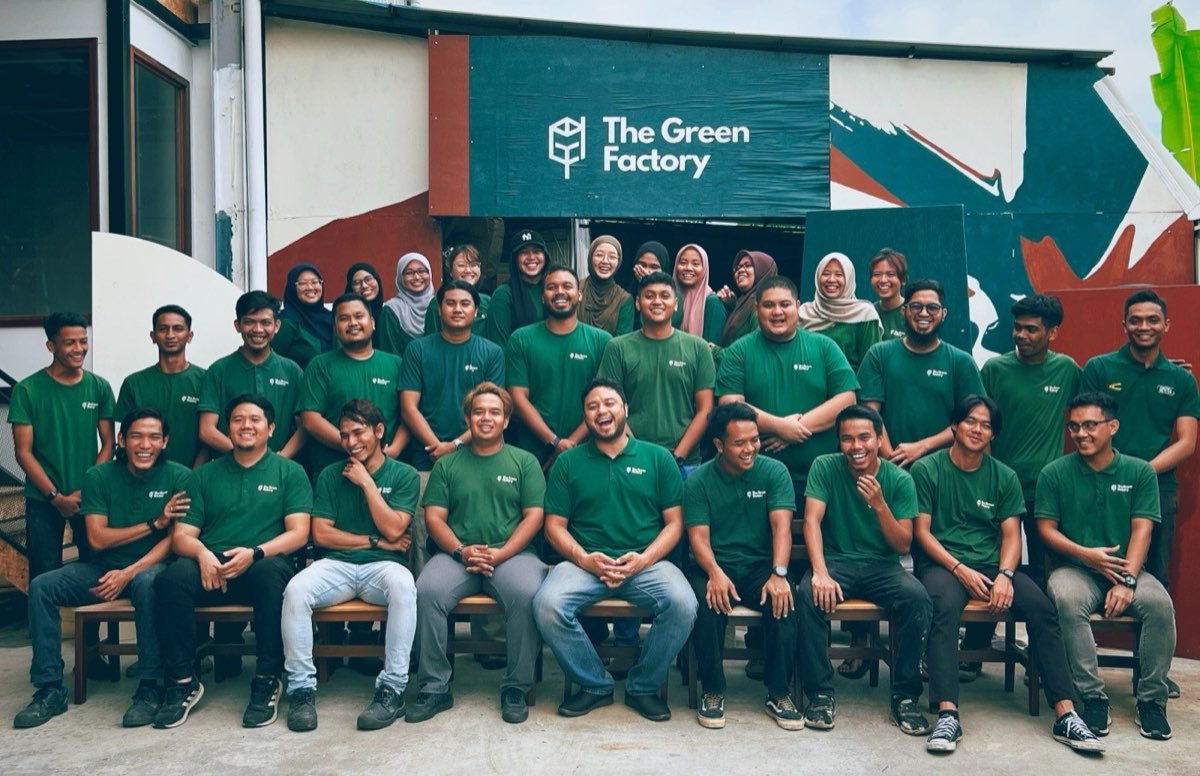 Pasukan The Green Factory di hadapan papan tanda kilang.